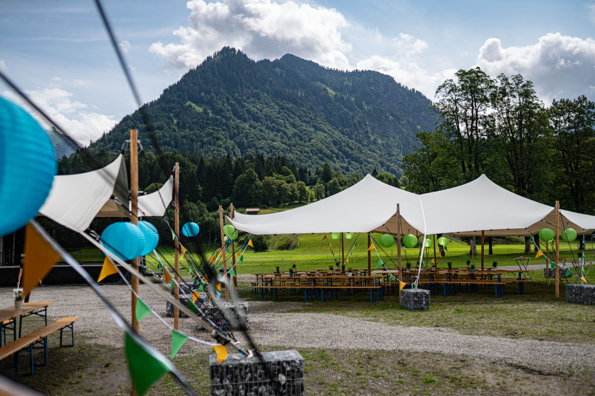 Stretchzelte und Sitzbereiche auf dem Gelände des Nordic Zentrums Oberstdorf vor der Bergkulisse der Allgäuer Alpen.