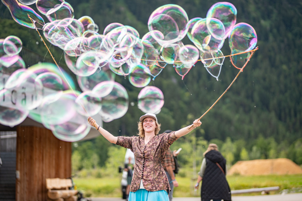 Seifenblasenkünstlerin begeistert Gäste beim OTT-JAKOB Firmenjubiläum mit großen Seifenblasen im Außenbereich des Nordic Zentrums Oberstdorf.