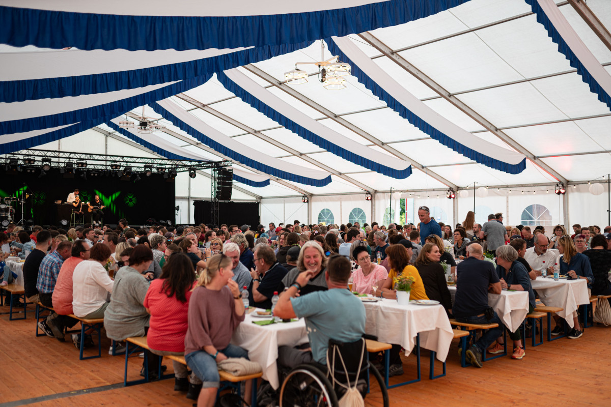 Mitarbeitende und Familienangehörige von OTT-JAKOB feiern gemeinsam im Festzelt mit Bühne und Livemusik während der Jubiläumsveranstaltung.