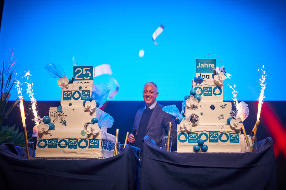 Vertreter des Unternehmens pr&auml;sentieren die Jubil&auml;umstorte auf der B&uuml;hne.
