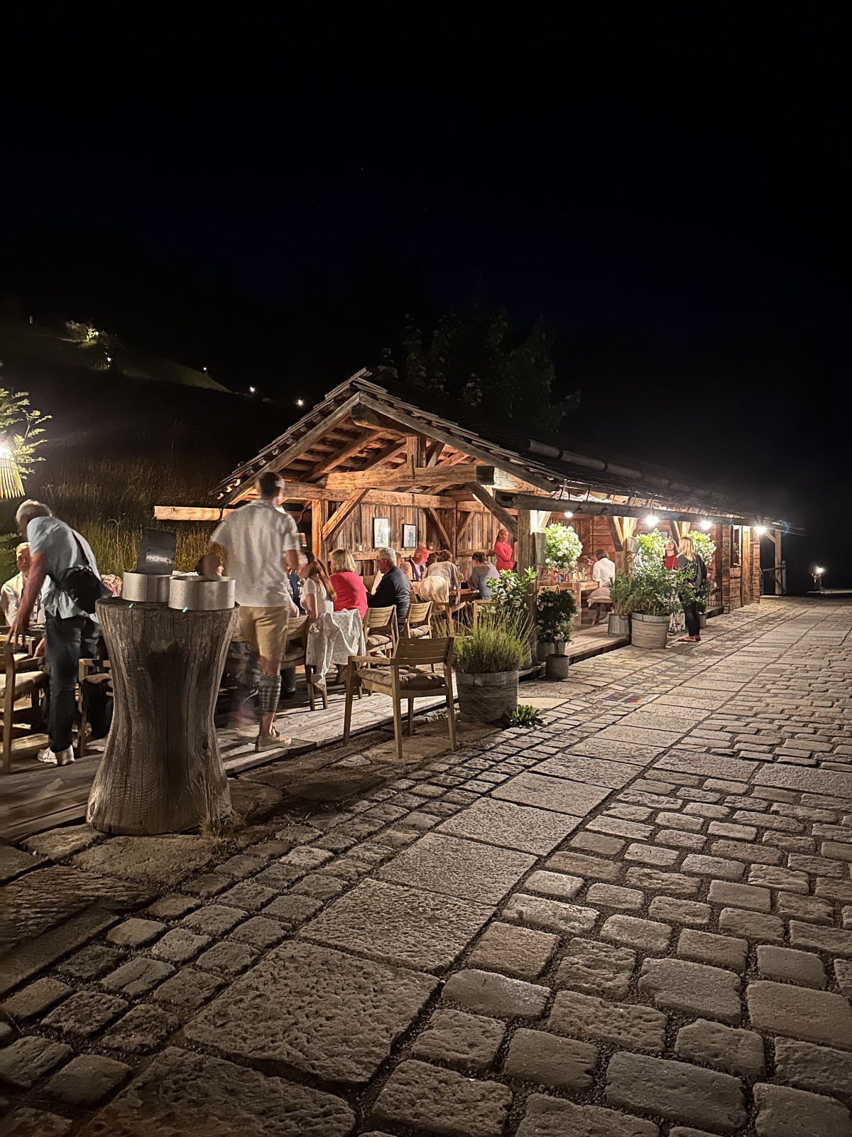 Evening event location with an illuminated hut and guests.
