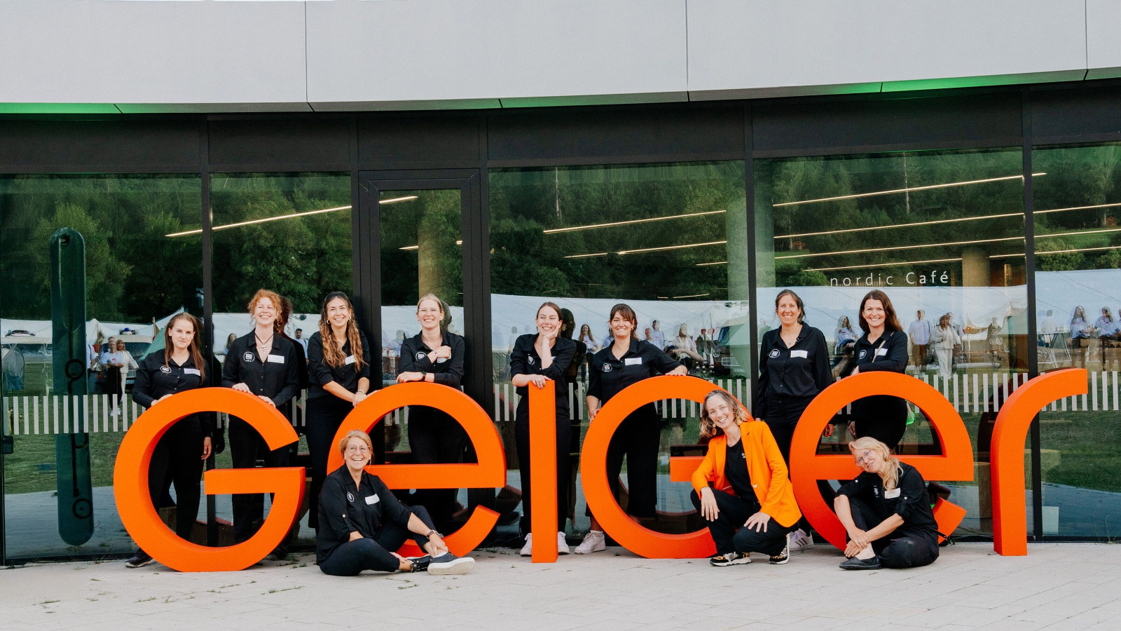 KAD team in front of the orange Geiger logo for the 100th anniversary.