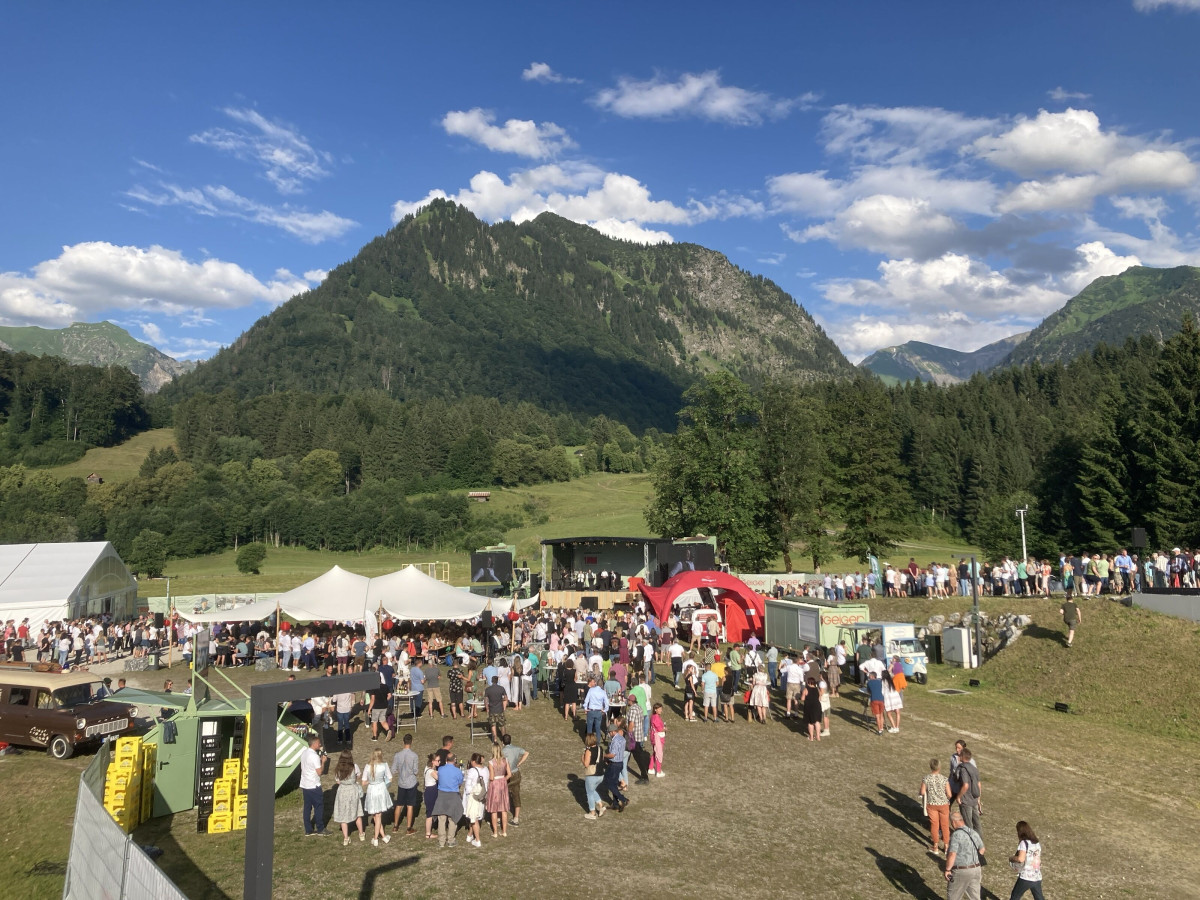Visitors on the anniversary grounds in front of a mountain panorama.