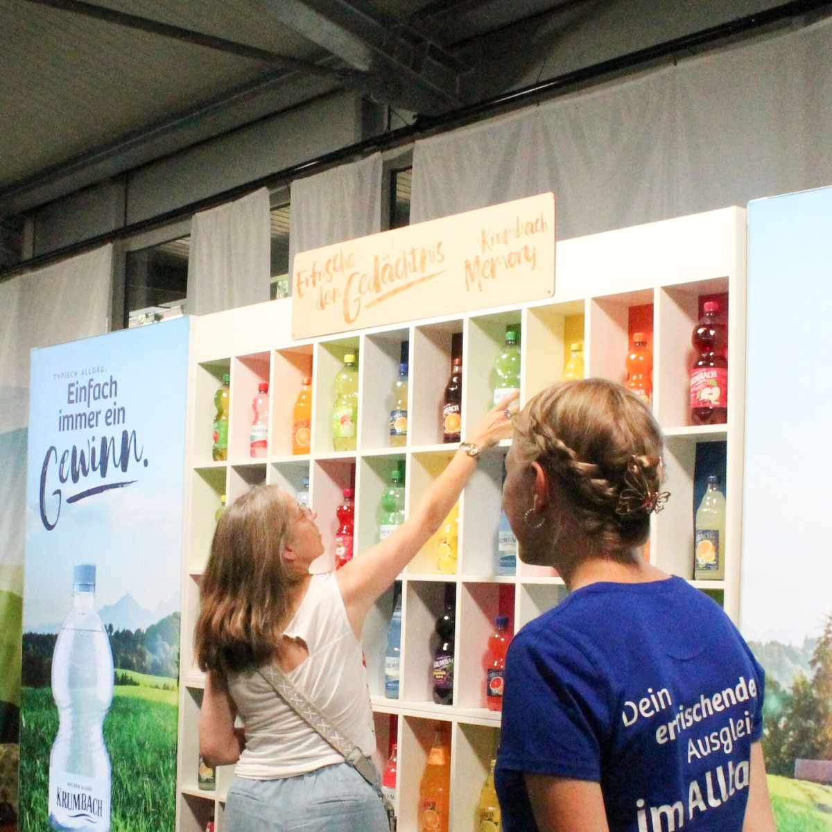 Visitors reach for colored bottles on the memory wall at the trade fair booth.
