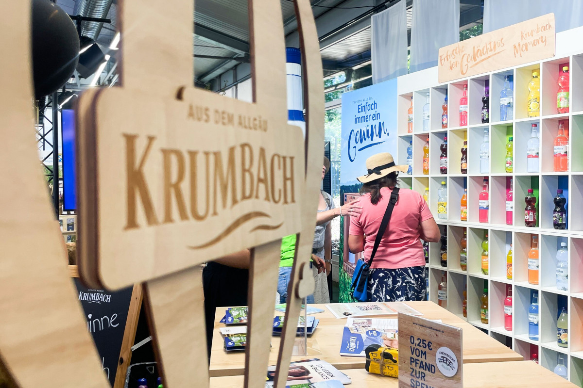Krumbach's booth at the festival week with wooden design elements and beverage presentation.