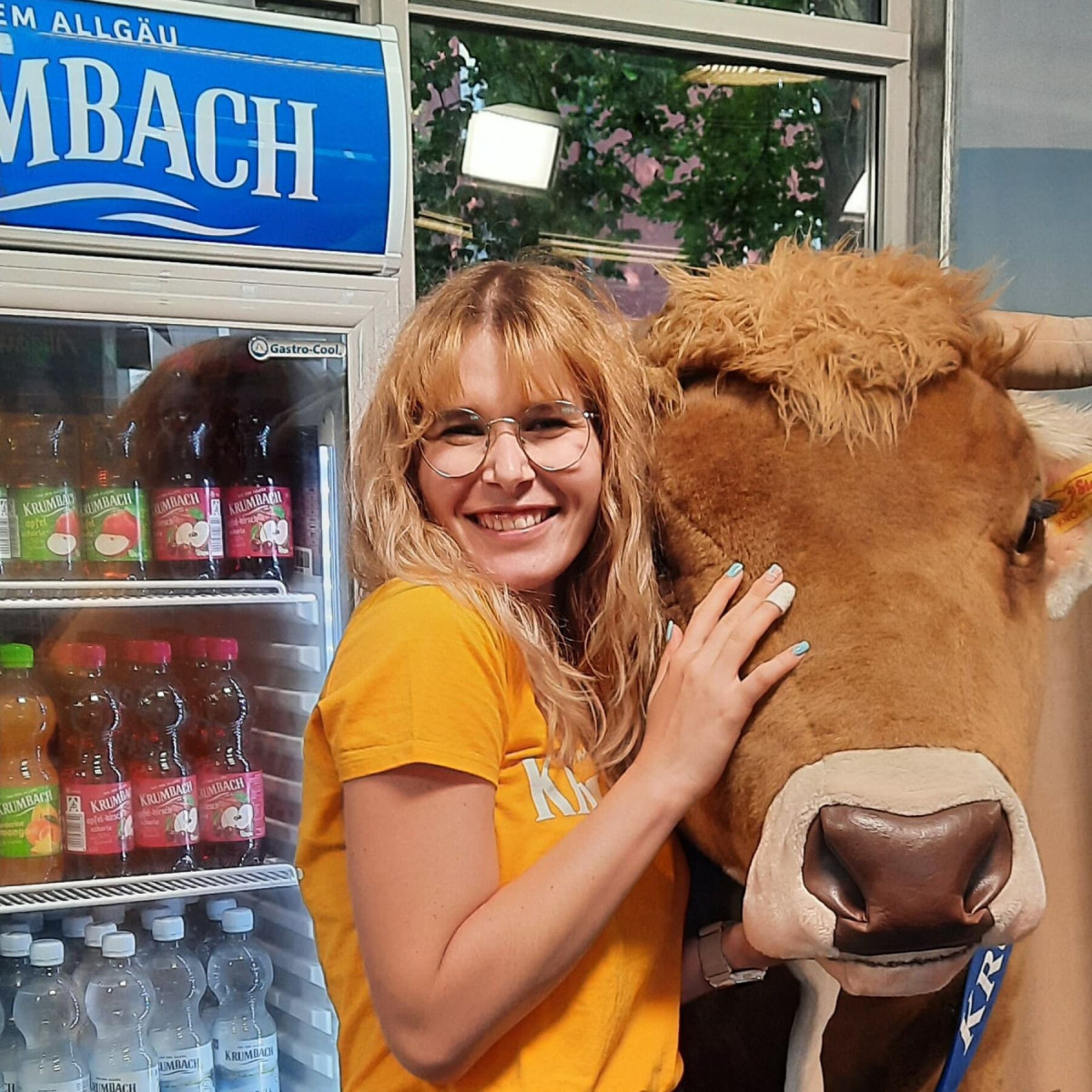 A booth host supports the memory game activity and poses with a life-size plush cow.