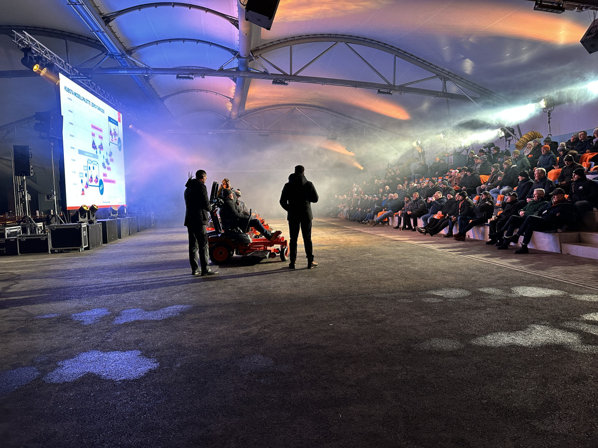 Produktpr&auml;sentation mit Maschine im Mittelpunkt vor sitzendem Publikum.