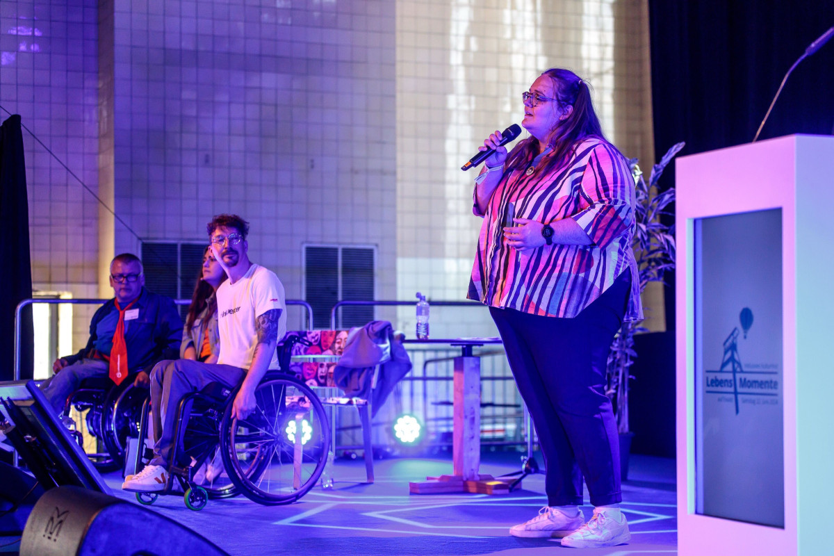 Vocal performance on stage in front of an illuminated backdrop.