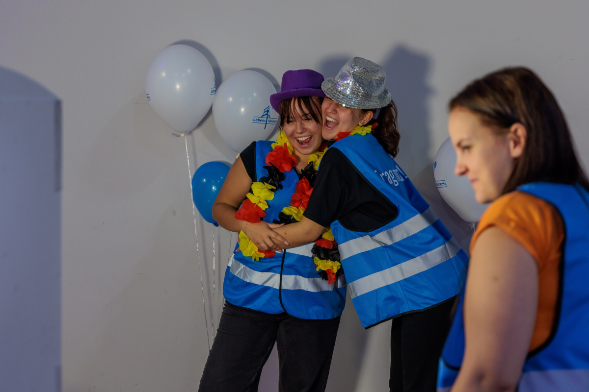 Two helpers test the photo booth, hug, and celebrate the shared moment.
