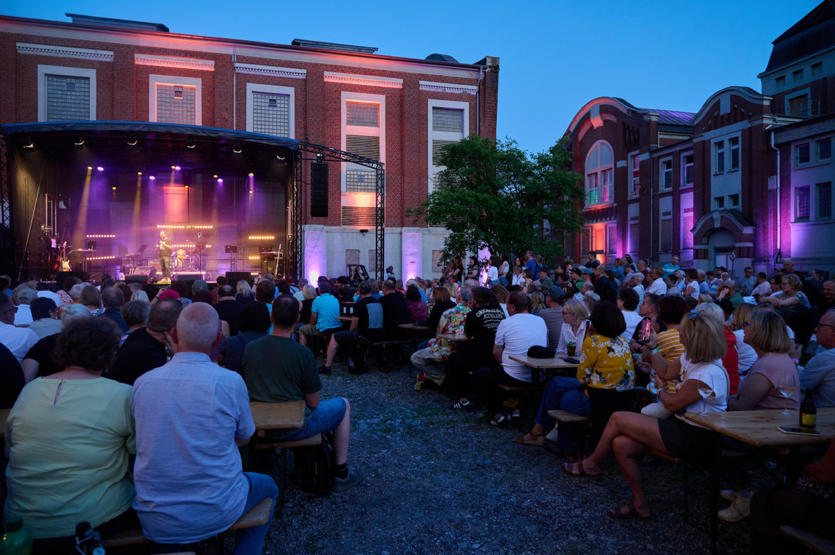 Visitors sit in front of the stage and follow a concert.