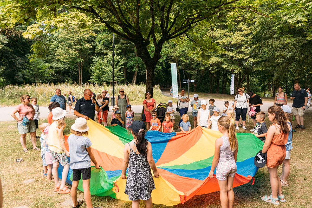 Children play together with a colorful parachute cloth on the meadow.