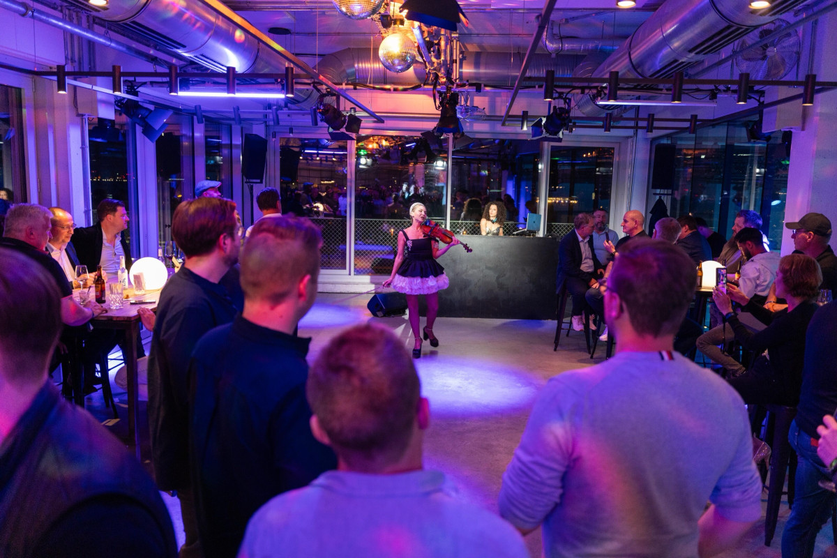 A violinist performs live for guests in an illuminated event venue.