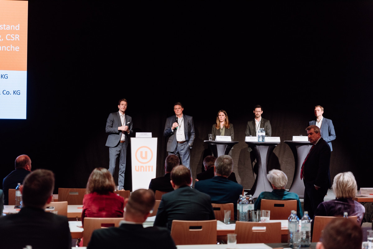 Panel discussion with speakers in front of a seated professional audience.