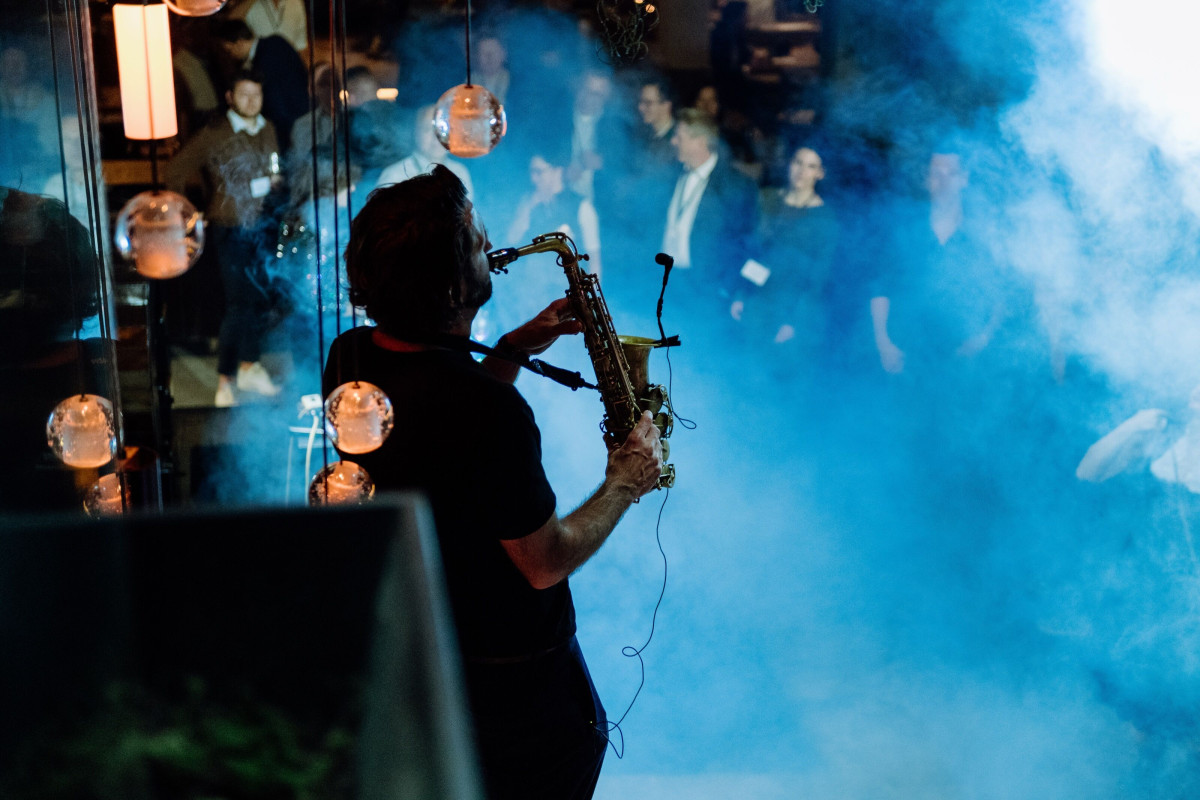 Evening event with live saxophone performance, lighting design, and audience.