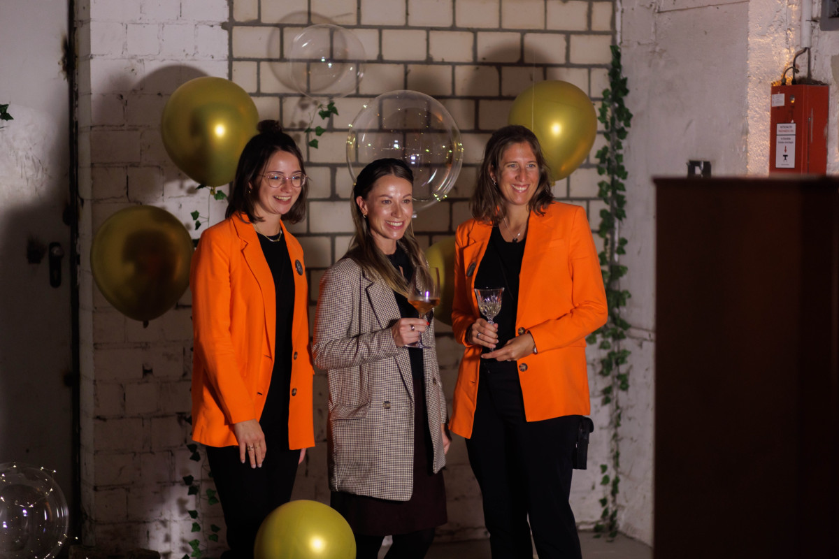 Attendees posing for a photo in front of a decorated backdrop at an event.